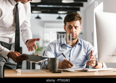 Upset business man having problems with work while sitting by the table in office Stock Photo