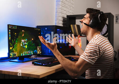 Portrait of upset angry guy wearing headset shouting while losing during play video games on computer Stock Photo