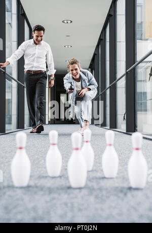 Happy businessman and businessman bowling in office passageway Stock Photo