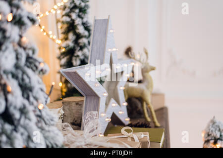 winter still life with Christmas decorations toy deer, star and gift boxes on light background. soft focus, blurred background Stock Photo