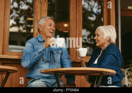 Portrait of senior couple sitting at table and drinking coffee in cafe. Happy elderly couple talking and enjoying a cup of coffee at cafe. Stock Photo