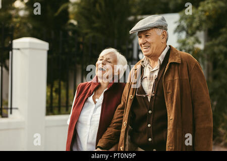 Portrait of old man and woman wearing warm clothing walking together outdoors and smiling. Senior couple enjoying walking together on a winter day. Stock Photo