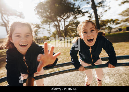 Two little twins playing together in playground outdoors. Identical twins having fun outdoors looking at camera and laughing. Stock Photo