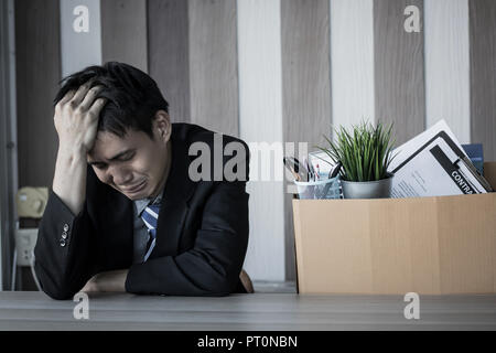 Sad fired executive man crying packing her stuff on a box at the office ...