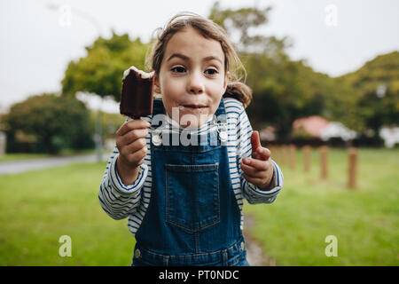 Portrait of adorable little girl enjoying eating ice cream. Cute young girl eating chocolate candy icecream. Stock Photo