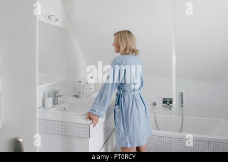 Smiling mature woman looking in bathroom mirror Stock Photo