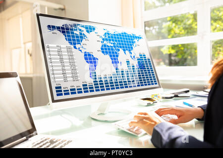 Young Businesswoman Analyzing Graphs On Computer At Workplace Stock Photo