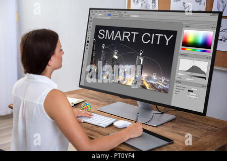 Female Designer Editing Image In Computer Using Graphic Tablet Stock Photo