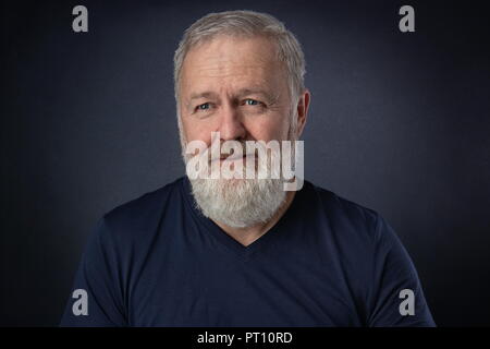 Happy 60 year old man with gray beard posing in the studio Stock Photo