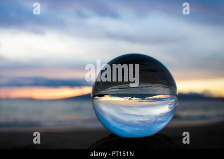Seascape sunset with island on horizon captured in reflection in glass ball Stock Photo