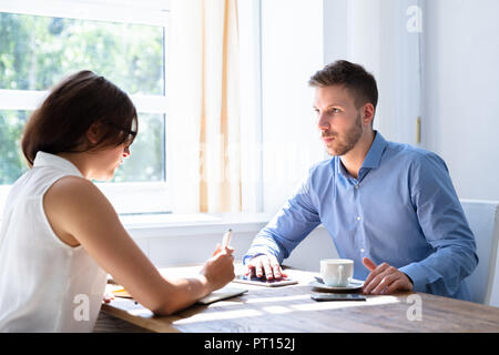 Side View Of Two Young Businesspeople Having Discussion In Office Stock Photo