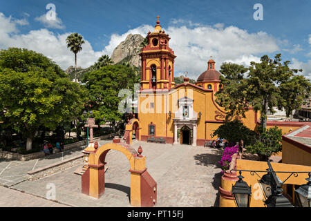 The Parroquia San Sebastian church with the massive monolith rock called the Pena de Bernal in the beautiful colonial village of Bernal, Queretaro, Mexico. Bernal is a quaint colonial town known for the Pena de Bernal, a giant monolith which dominates the tiny village is the third highest on the planet. Stock Photo