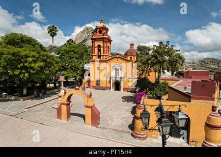 The Parroquia San Sebastian church with the massive monolith rock called the Pena de Bernal in the beautiful colonial village of Bernal, Queretaro, Mexico. Bernal is a quaint colonial town known for the Pena de Bernal, a giant monolith which dominates the tiny village is the third highest on the planet. Stock Photo