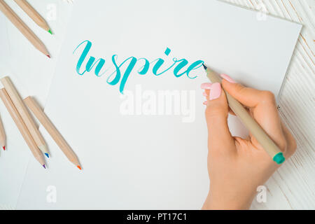 Calligrapher student practices in writing word inspire with green marker on canvas. Creative artist freelancer working on project at home studio. Lett Stock Photo