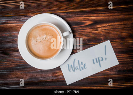 Wake up text near cup of coffee. Font of lettering word on white paper by calligrapher. Morning, handwriting, lettering, concept. Stock Photo