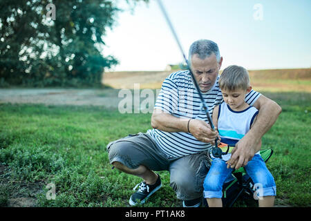 Grandfather and grandson fishing together at lakeshore Stock Photo