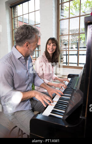 Mature couple having fun at home, playing the piano Stock Photo
