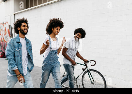 Three friends with racing cycle walking on the street Stock Photo