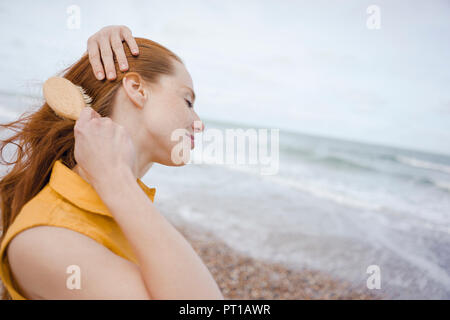 Woman using hair brush at the sea Stock Photo