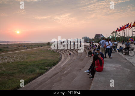 Tourists and local people sitting and relaxing at the popular Mekong Riverside Park in Vientiane, Laos, at sunset. Stock Photo