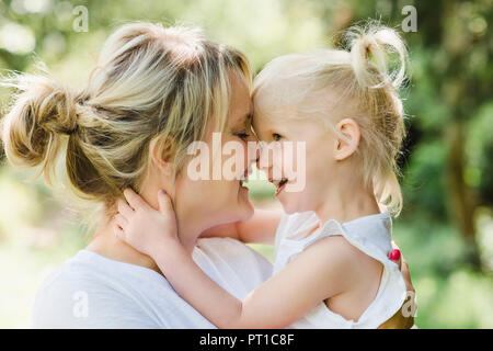 Happy mother cuddling her daughter in nature Stock Photo
