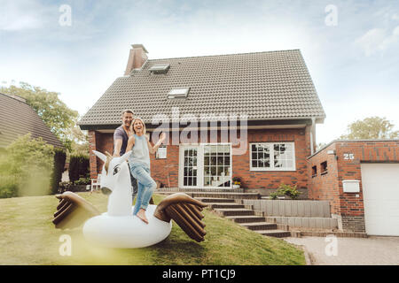 Happy mature couple with inflatable pool toy in garden of their home Stock Photo