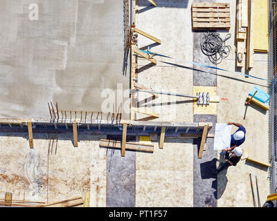Worker and architect looking at blueprint on construction site Stock Photo