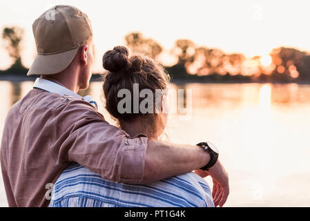 Young couple watching the sunset above a river Stock Photo