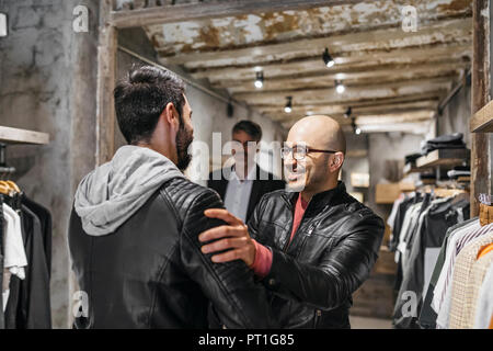 Two smiling men meeting in modern menswear shop Stock Photo