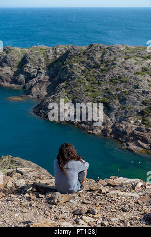 Man looking sitting on rocks, looking at the sea Stock Photo
