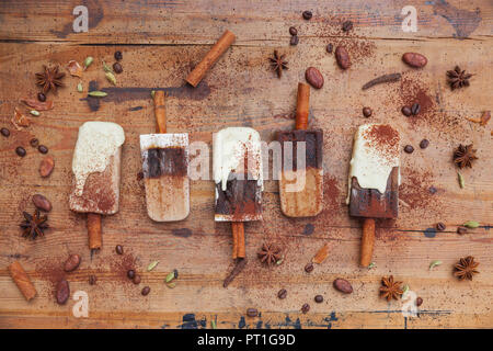 Homemade coffee and white chocolate ice lollies with winter spices on wooden background Stock Photo