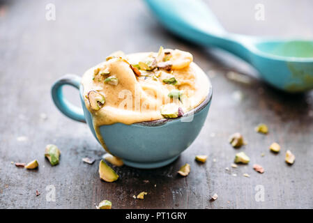Homemade saffron ice cream with pistachio nuts, melting Stock Photo