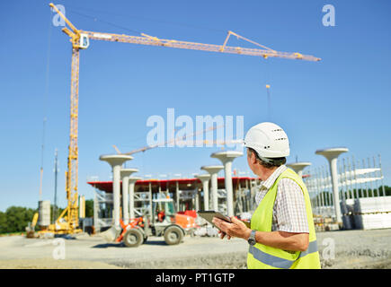 Worker on construction site using digital tablet Stock Photo