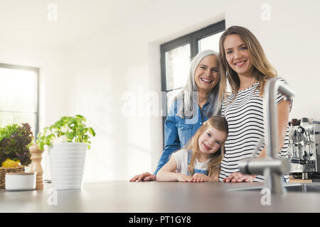Happy three generations family standing in kitchen Stock Photo