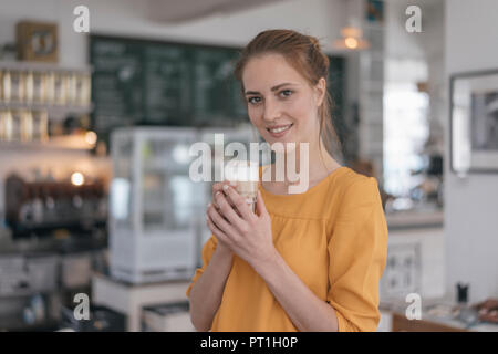 Young business owner standing in her coffee shop, drinking coffee Stock Photo