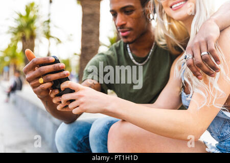 Hands of multicultural young couple holding smartphone Stock Photo