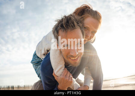 Couple at the beach, man carrying woman piggyback Stock Photo