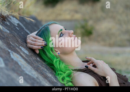 Young woman with dyed green hair and eyebrows in nature Stock Photo