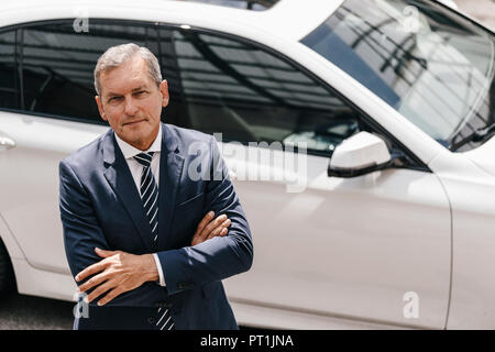 Portrait of mature businessman standing in front of car Stock Photo