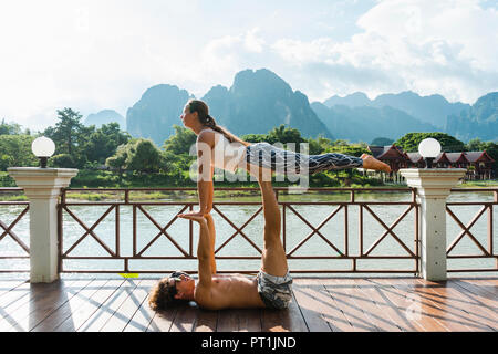 Laos, Vang Vieng, Young couple doing acro-yoga on a terrace Stock Photo