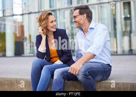 Two business people sitting outdoors talking Stock Photo
