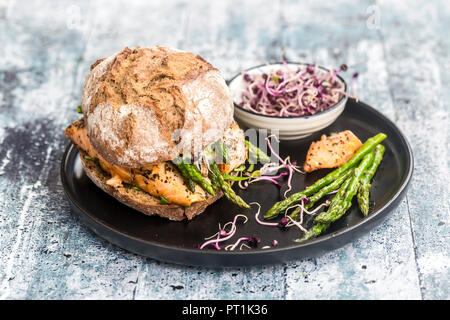 Salmon burger with green asparagus and red cress on plate Stock Photo