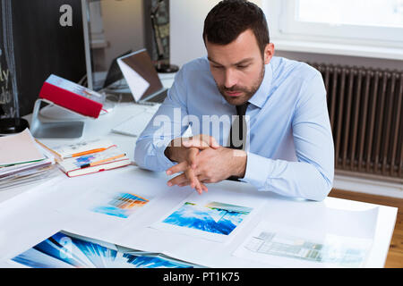 Businessman at desk in office looking at printouts Stock Photo