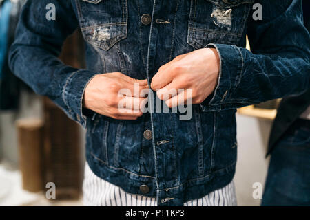 Man trying on new denim jacket Stock Photo