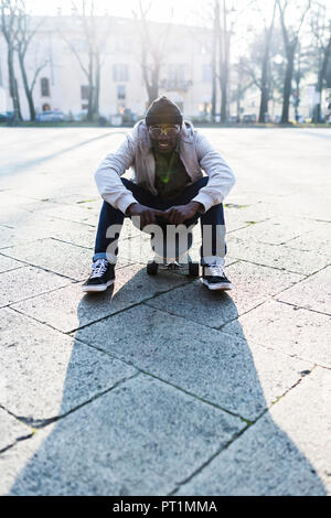 Young amn with skateboard on urban square Stock Photo