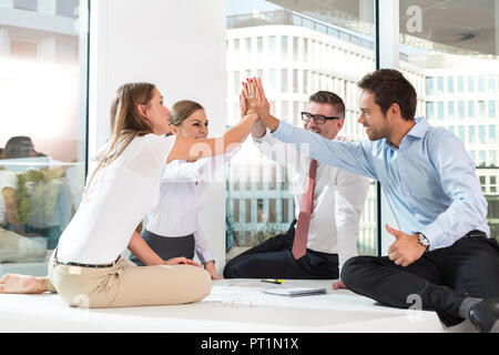 Poland, Warzawa, four successful businessmen sitting on conference table Stock Photo