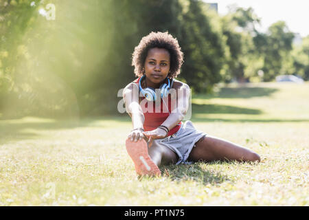 Young woman stretching on meadow in park Stock Photo