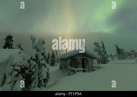 Northern lights on wood hut covered with snow, Pallas-Yllastunturi National Park, Muonio, Lapland, Finland Stock Photo