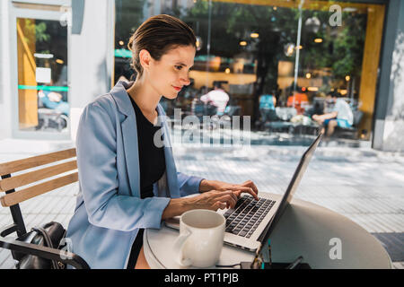 Young businesswoman sitting in coffee shop, using laptop Stock Photo