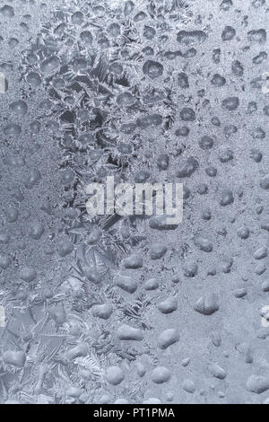 White frosty pattern formed from lot of frozen water drops on winter window. Stock Photo